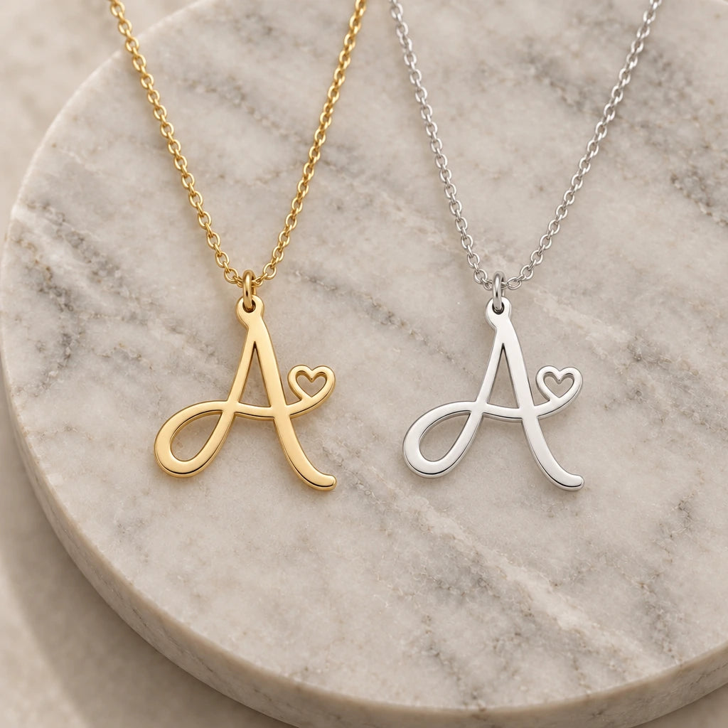 Silver and gold a initial heart pendant necklaces side by side on marble