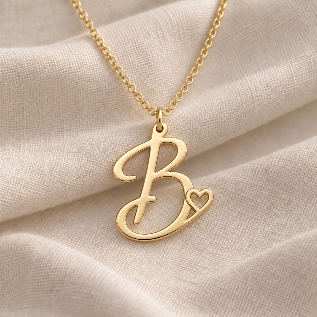 B Initial Heart pendant necklace in a warm gold finish on cream fabric
