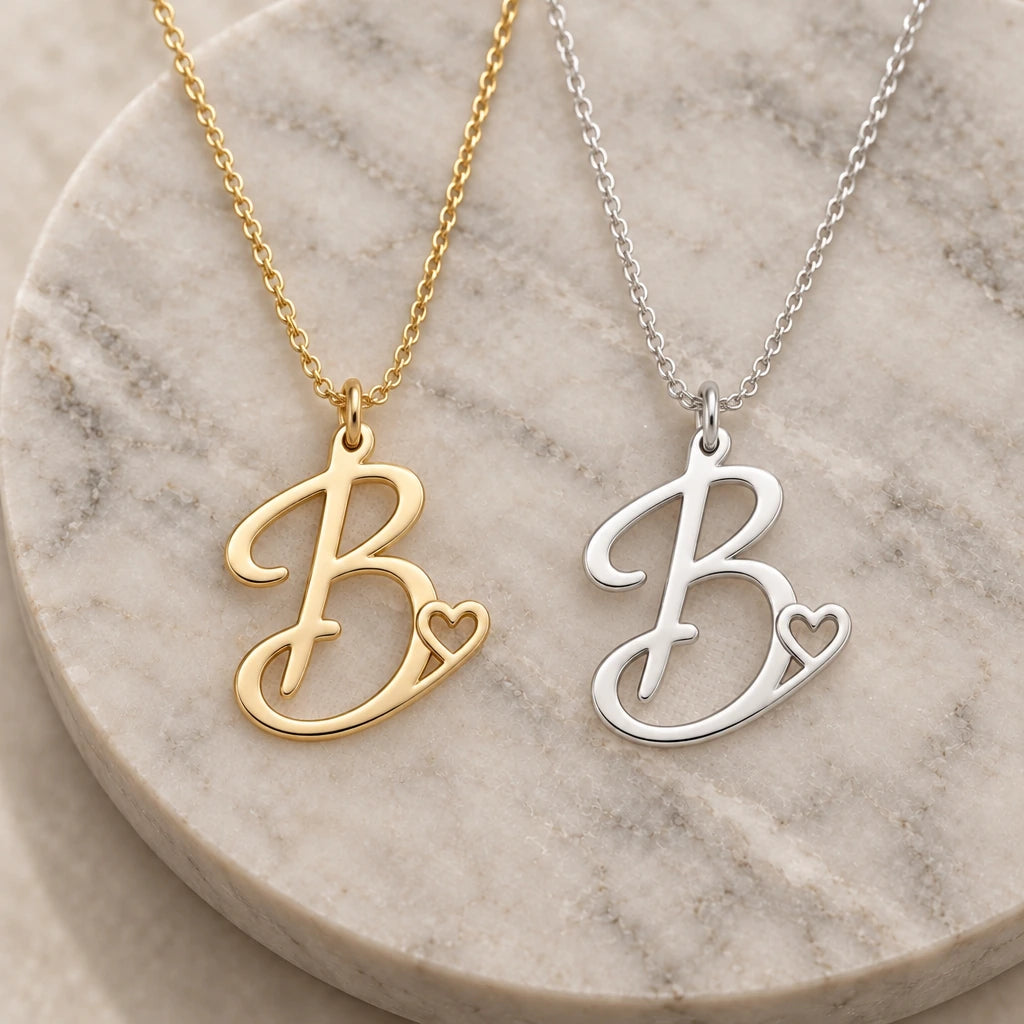 Silver and gold b initial heart pendant necklaces side by side on marble