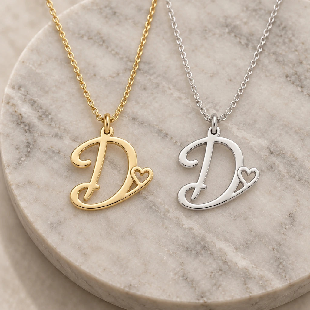 Silver and gold d initial heart pendant necklaces side by side on marble