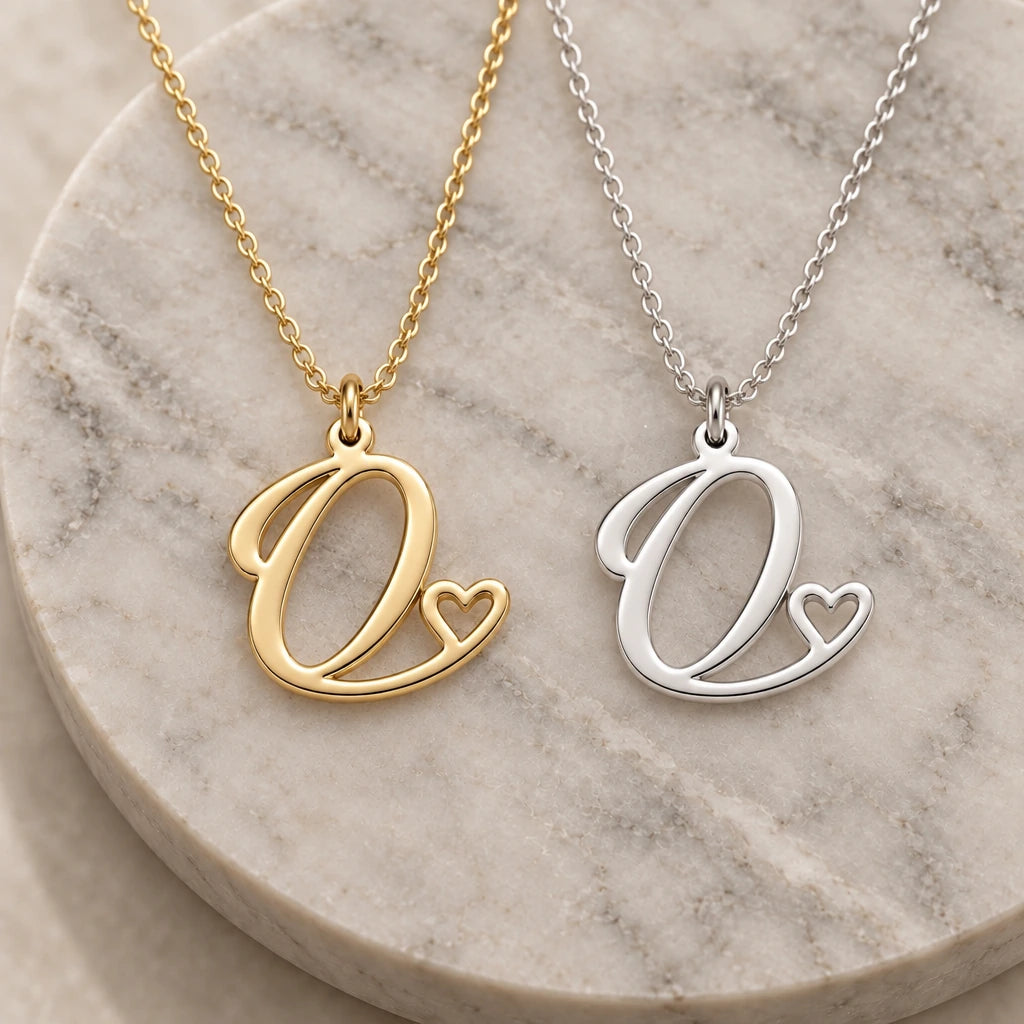 Silver and gold o initial heart pendant necklaces side by side on marble
