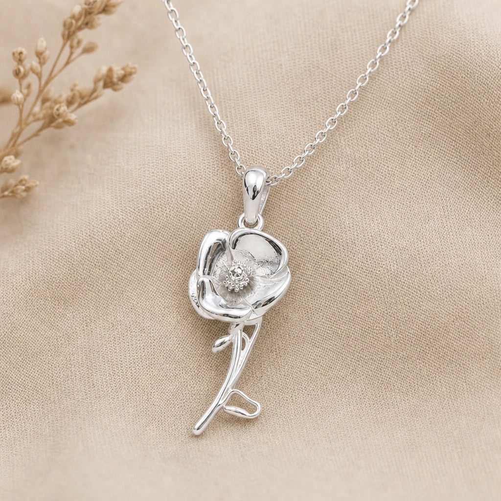 Close-up of silver poppy pendant with cupped petals, stem and bud