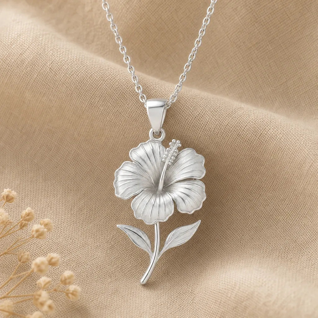 Close-up of silver hibiscus flower pendant with finely sculpted petals, stamens, stem and leaves