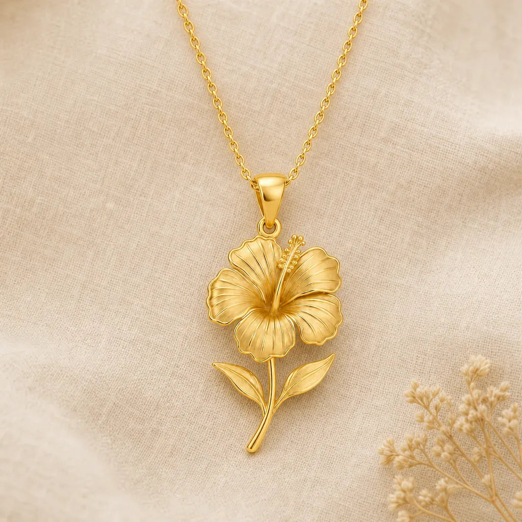 Hibiscus flower pendant necklace in a warm gold finish on cream fabric