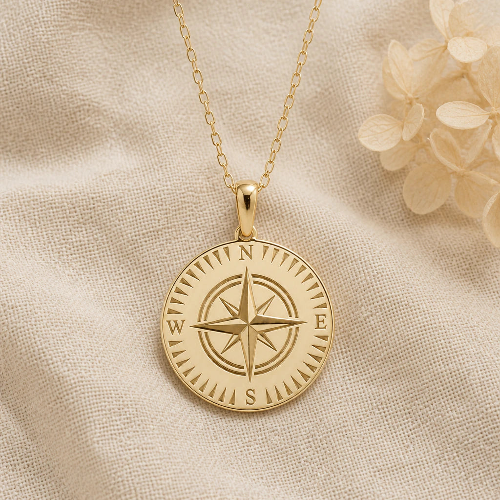 Compass pendant necklace in a warm gold finish on cream fabric