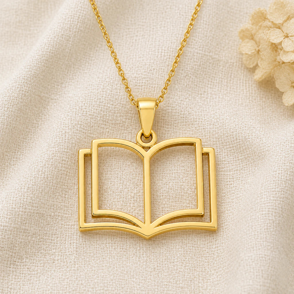 Open Book pendant necklace in a warm gold finish on cream fabric