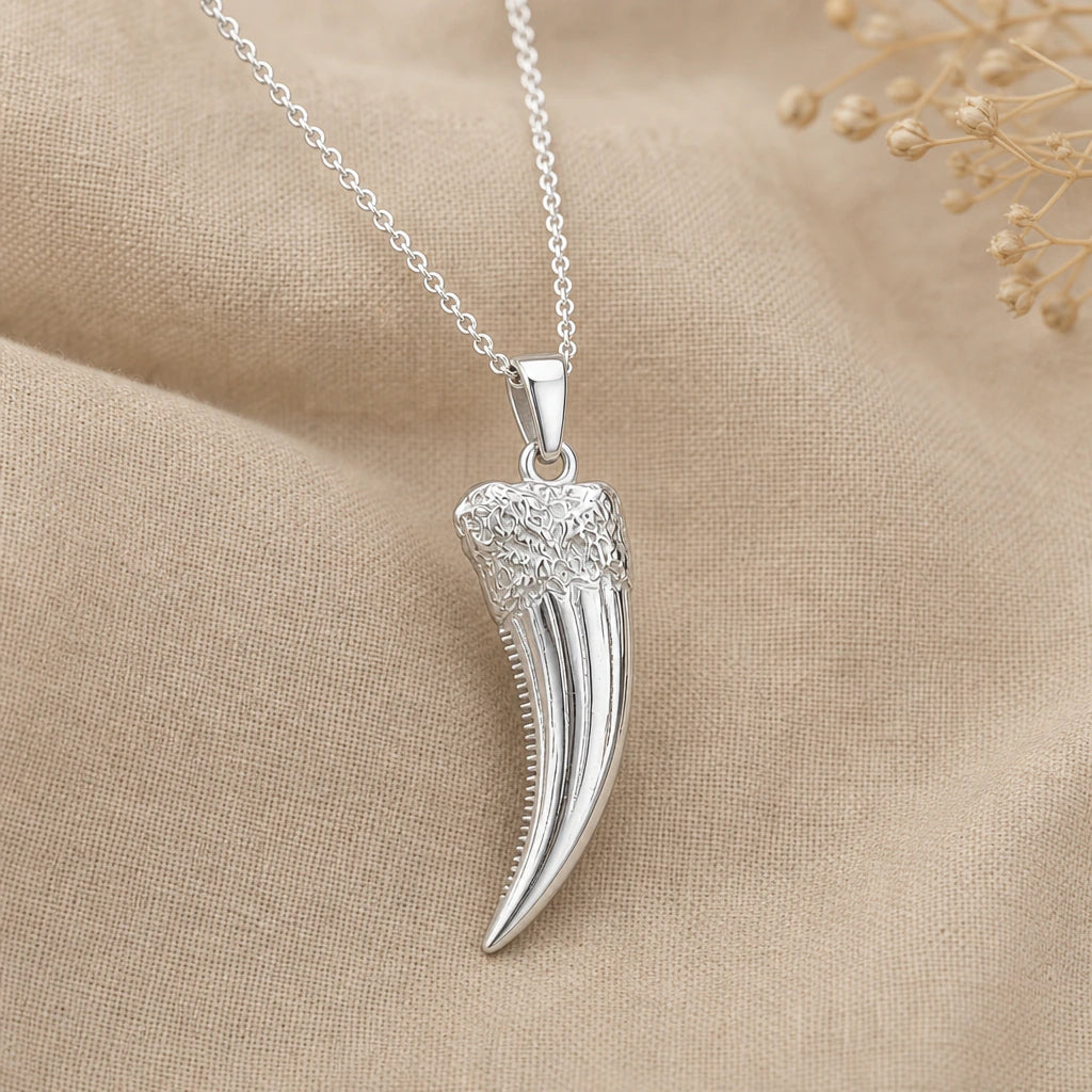 Close-up of silver sabre tooth fang pendant with textured root and serrated edge