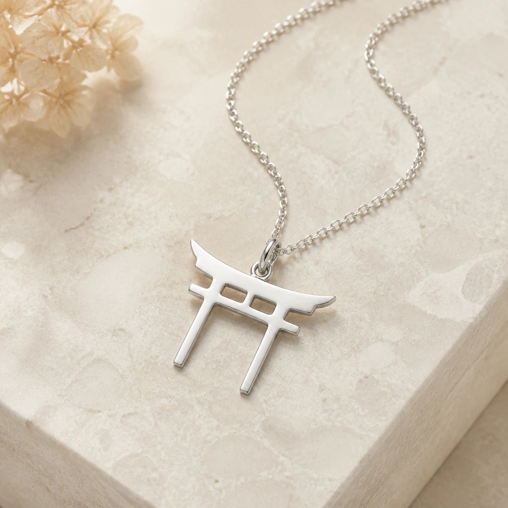Close-up of silver torii gate pendant showing the sculpted detail