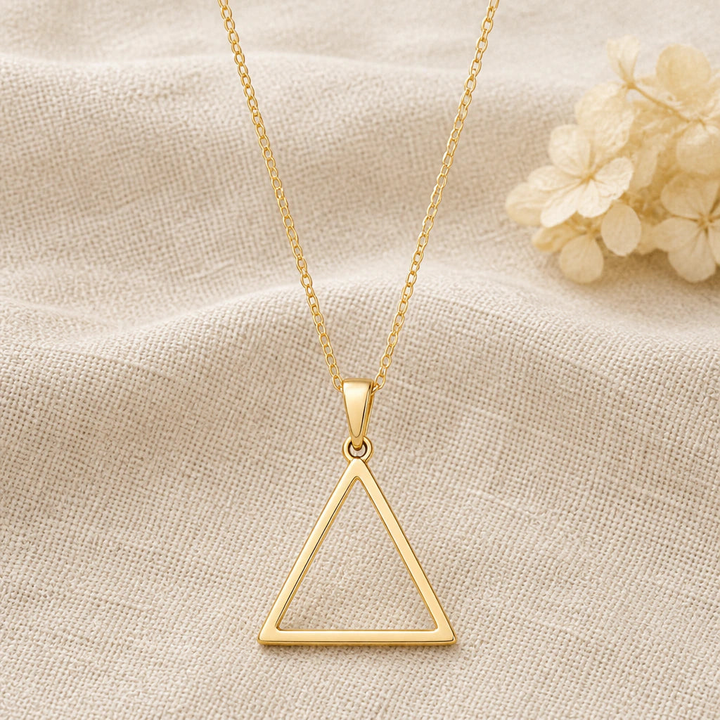 Water Element Triangle pendant necklace in a warm gold finish on cream fabric