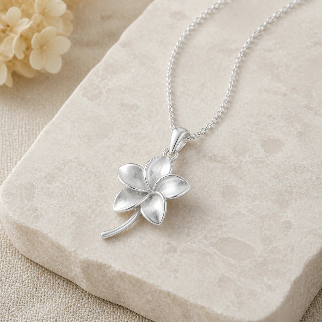 Close-up of silver plumeria flower pendant showing the sculpted detail
