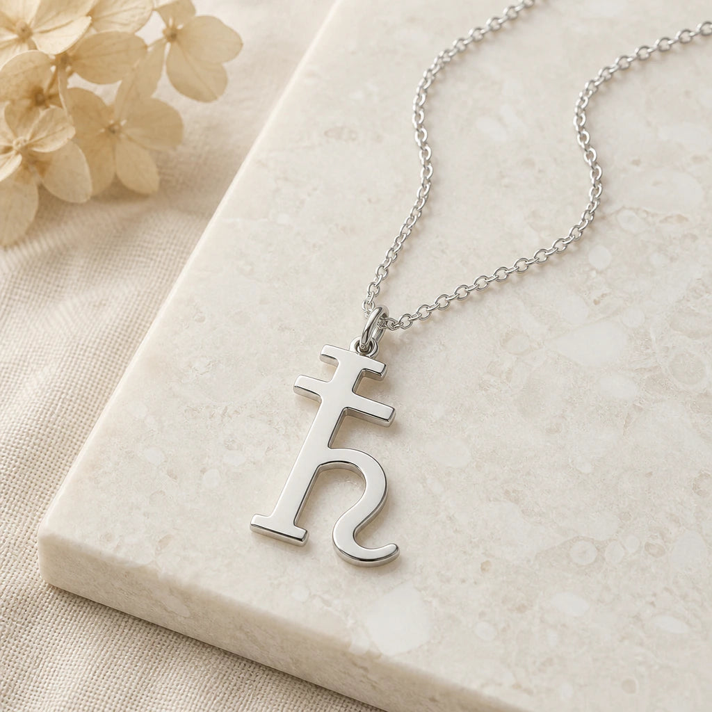 Close-up of silver saturn symbol pendant showing the sculpted detail