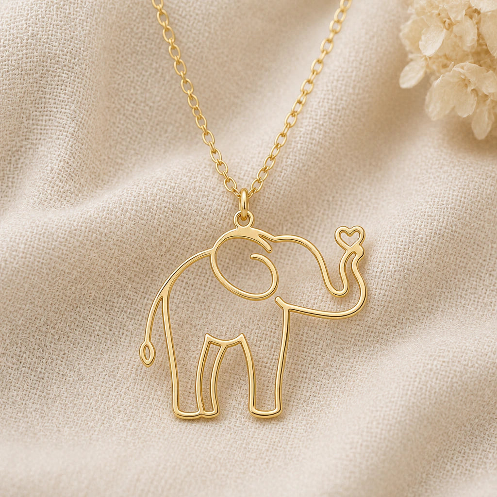 Elephant Outline pendant necklace in a warm gold finish on cream fabric