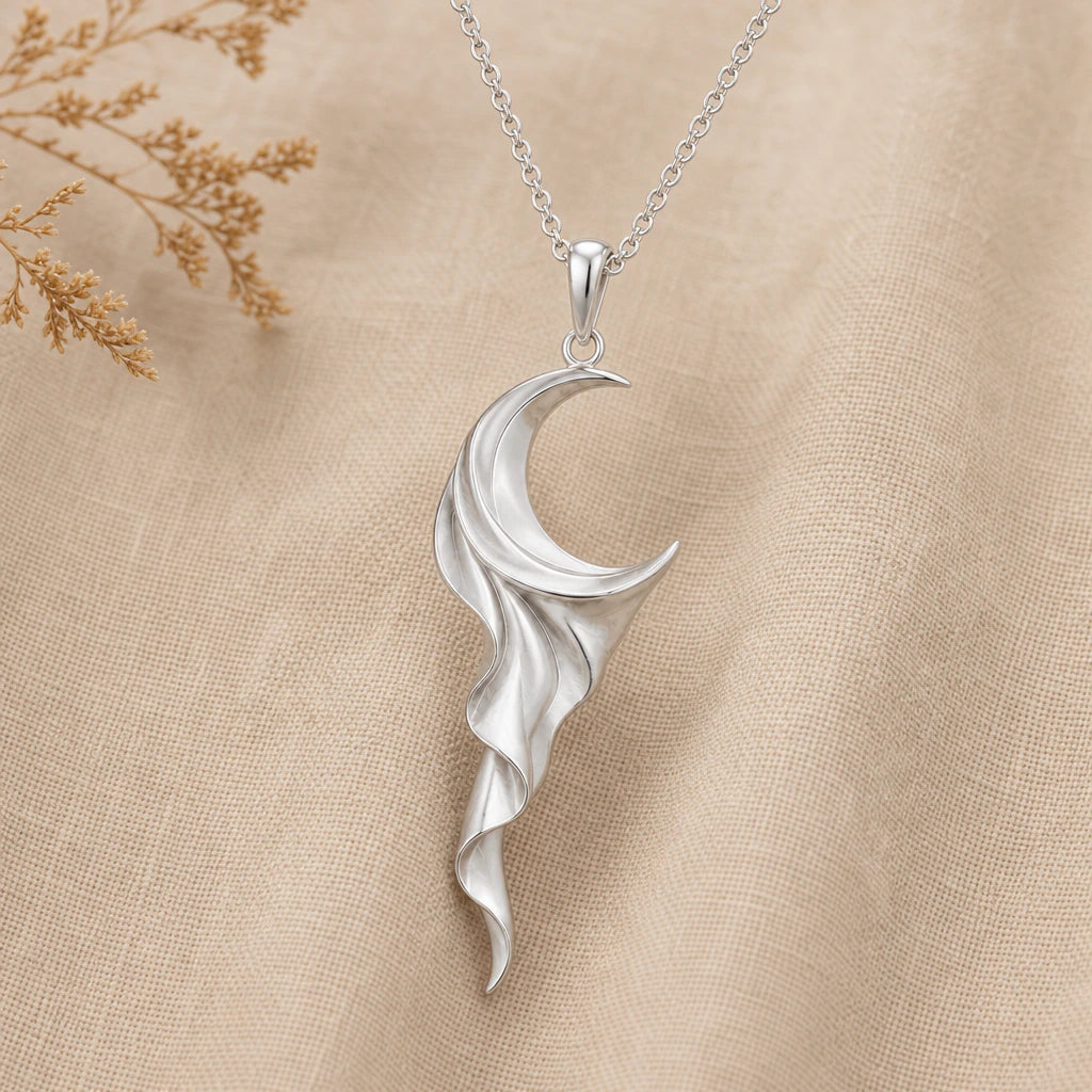 Close-up of silver crescent moon pendant with draped silk folds