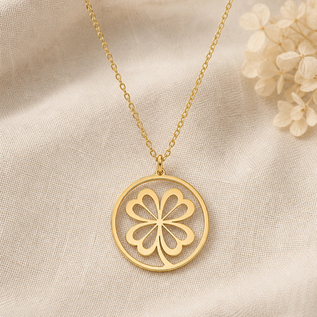 Four Leaf Clover pendant necklace in a warm gold finish on cream fabric