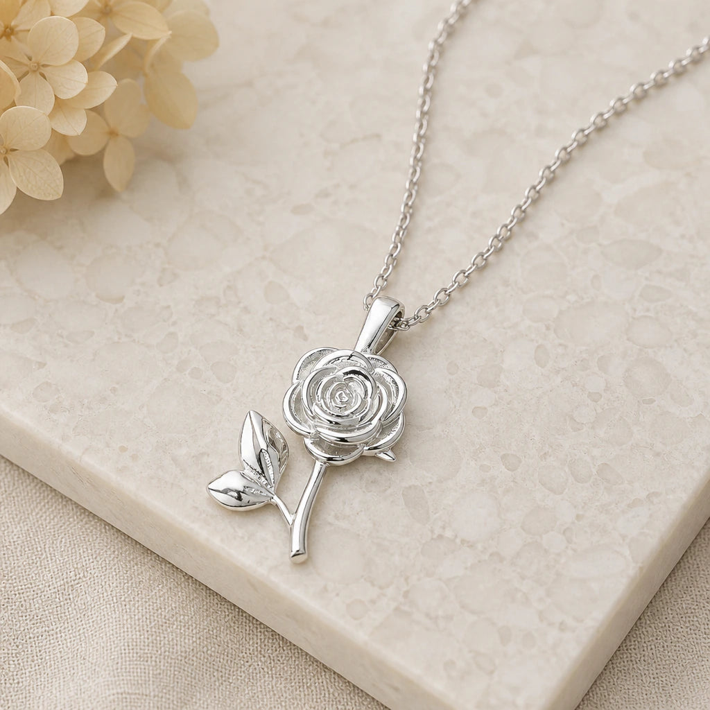 Close-up of silver rose birth flower pendant showing the sculpted detail
