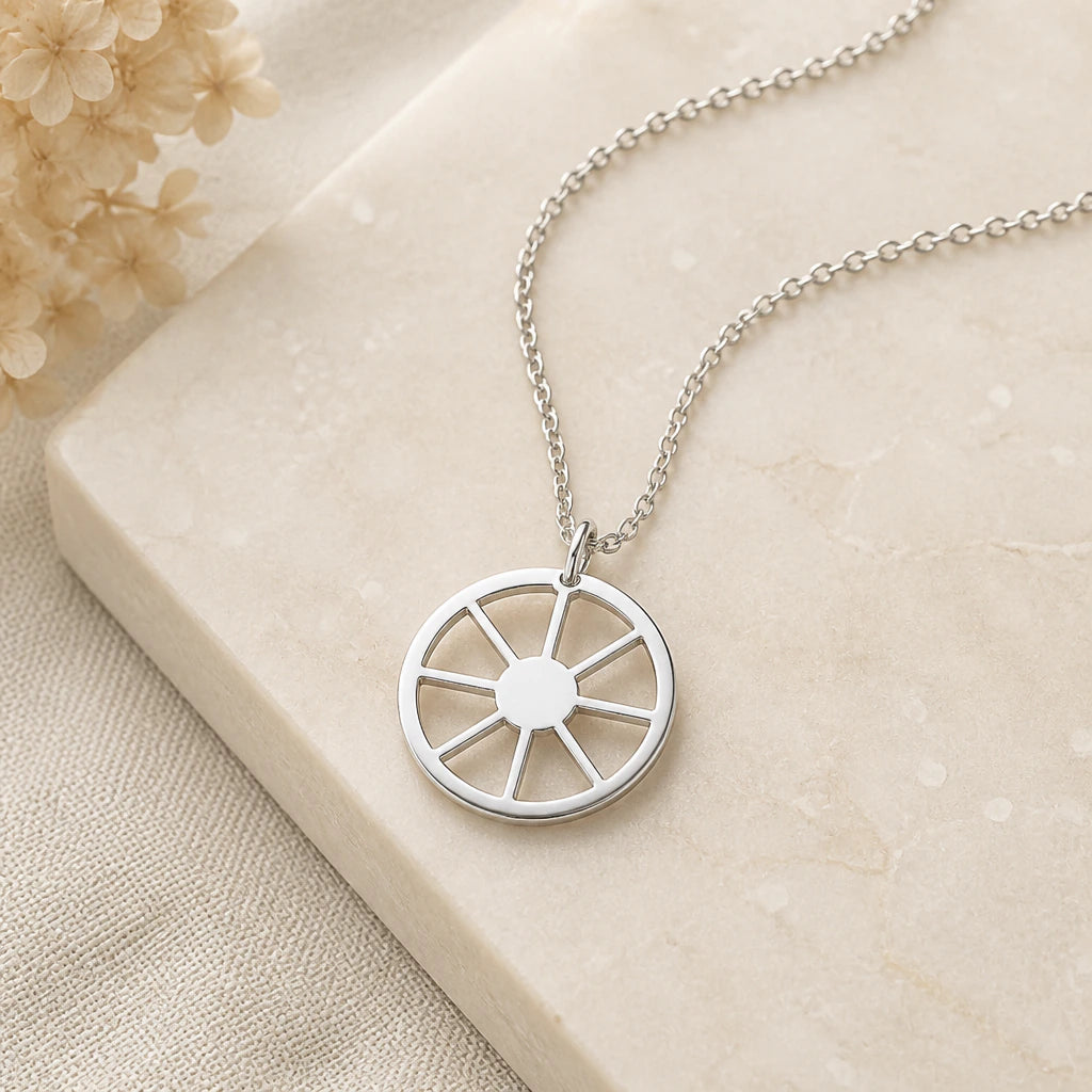 Close-up of silver sun wheel symbol pendant showing the sculpted detail