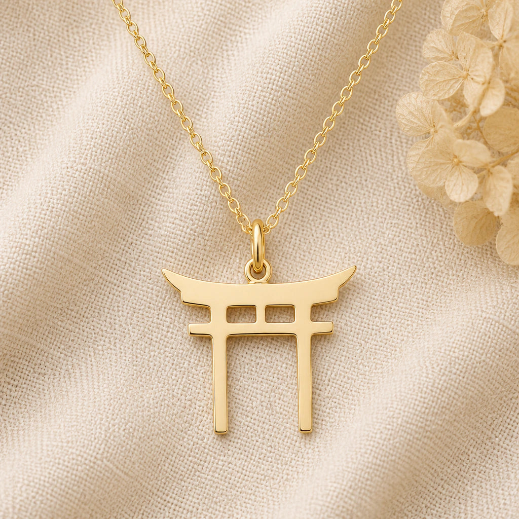 Torii Gate pendant necklace in a warm gold finish on cream fabric