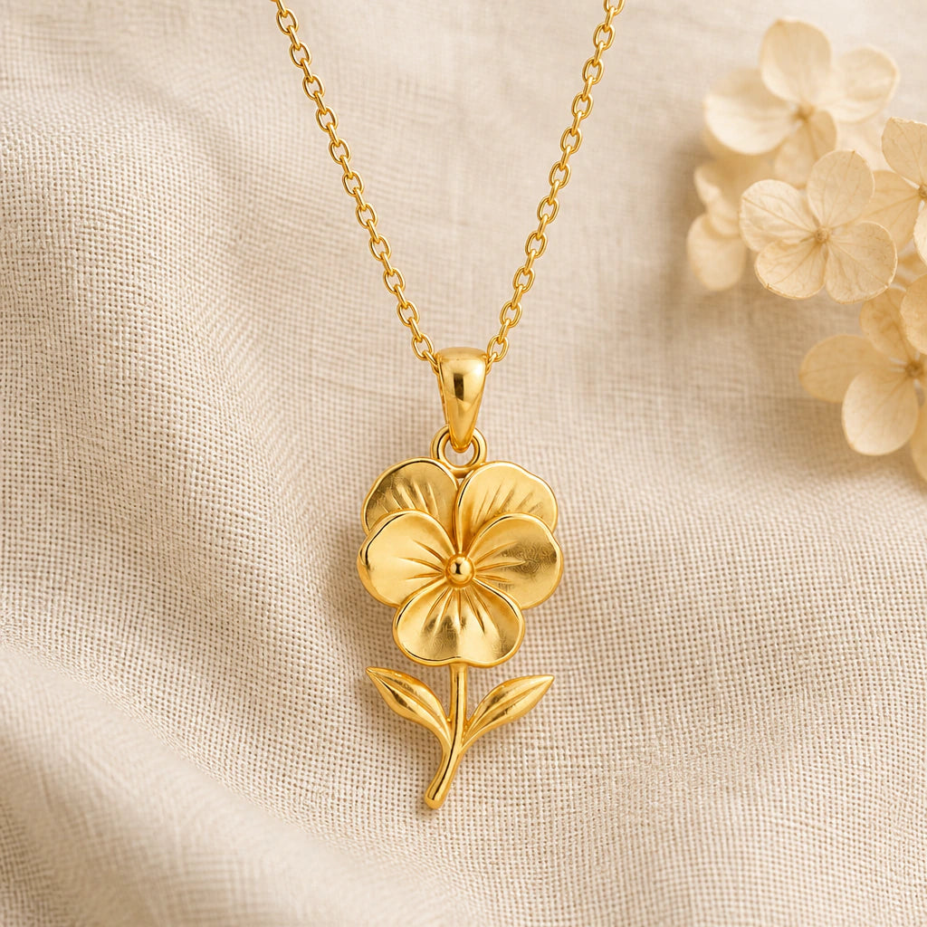 Pansy Flower pendant necklace in a warm gold finish on cream fabric