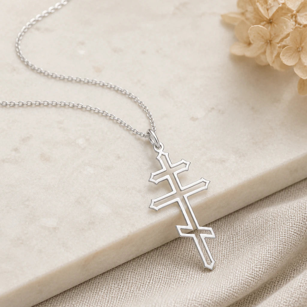 Close-up of silver orthodox cross pendant showing the sculpted detail