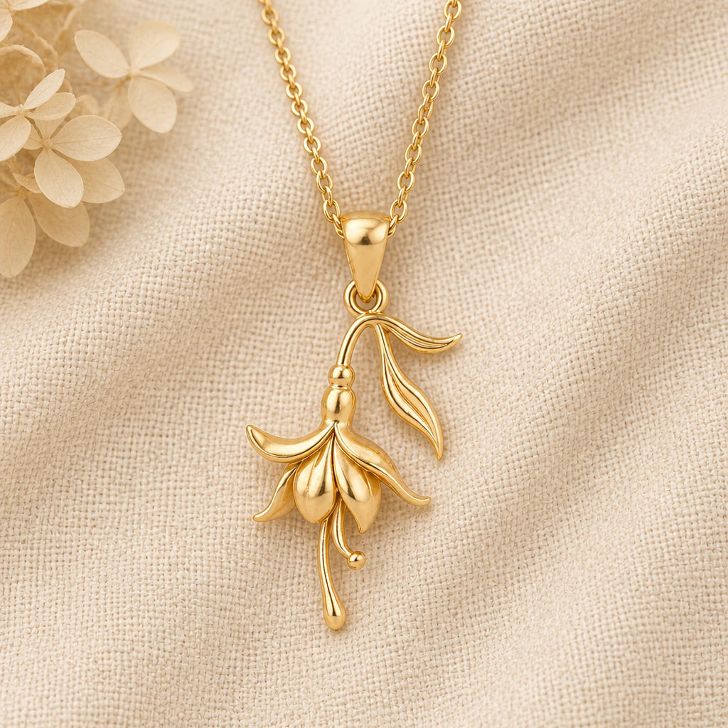 Fuchsia Flower pendant necklace in a warm gold finish on cream fabric