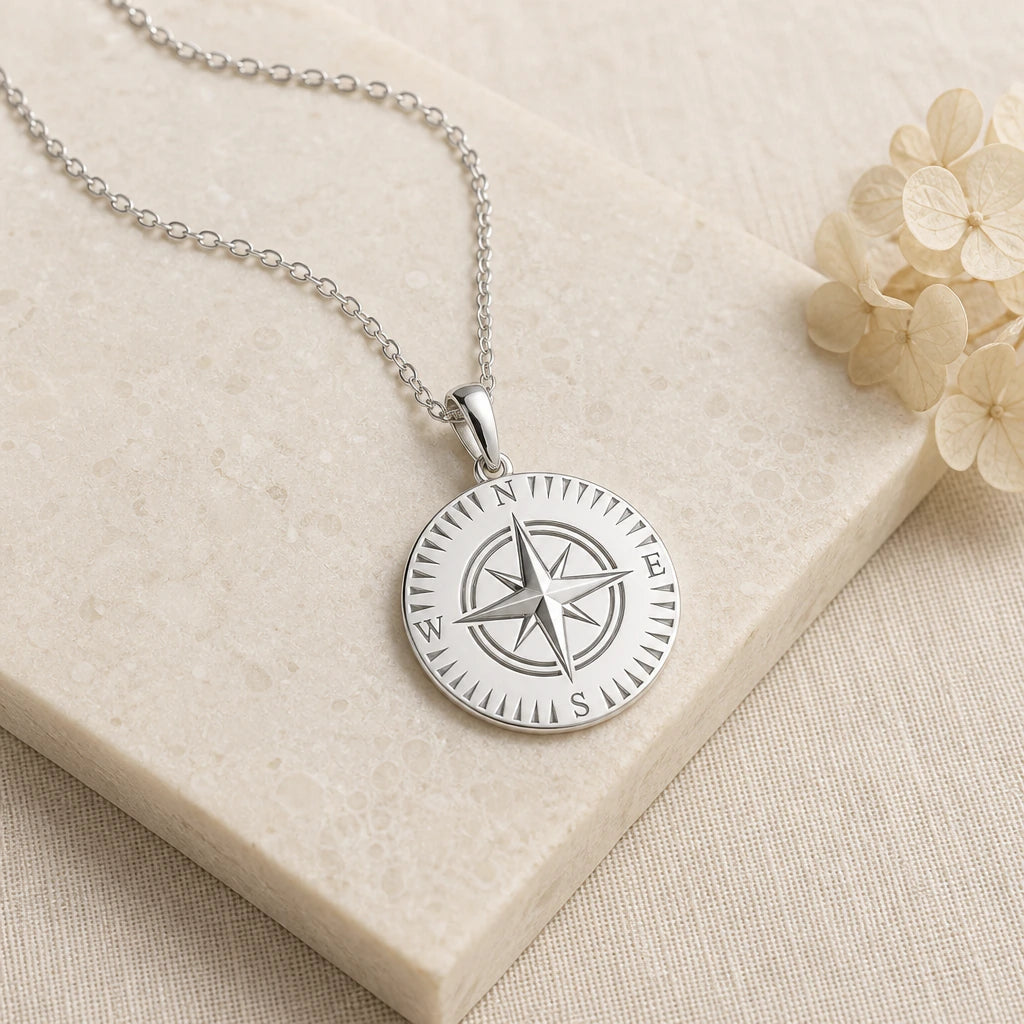 Close-up of silver compass pendant showing the sculpted detail