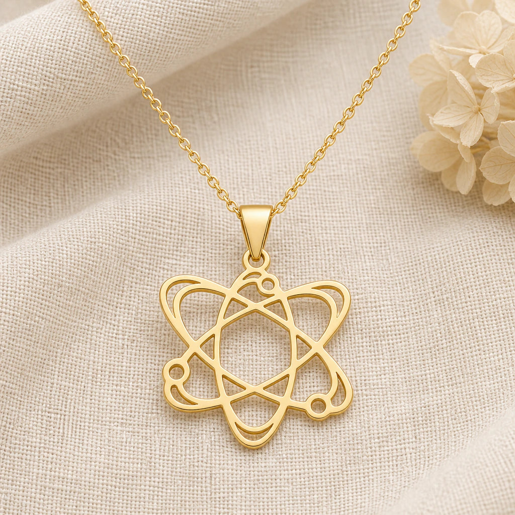 Atom pendant necklace in a warm gold finish on cream fabric
