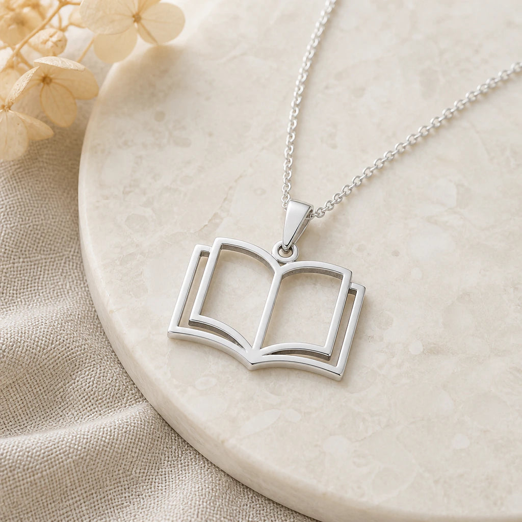 Close-up of silver open book pendant showing the sculpted detail