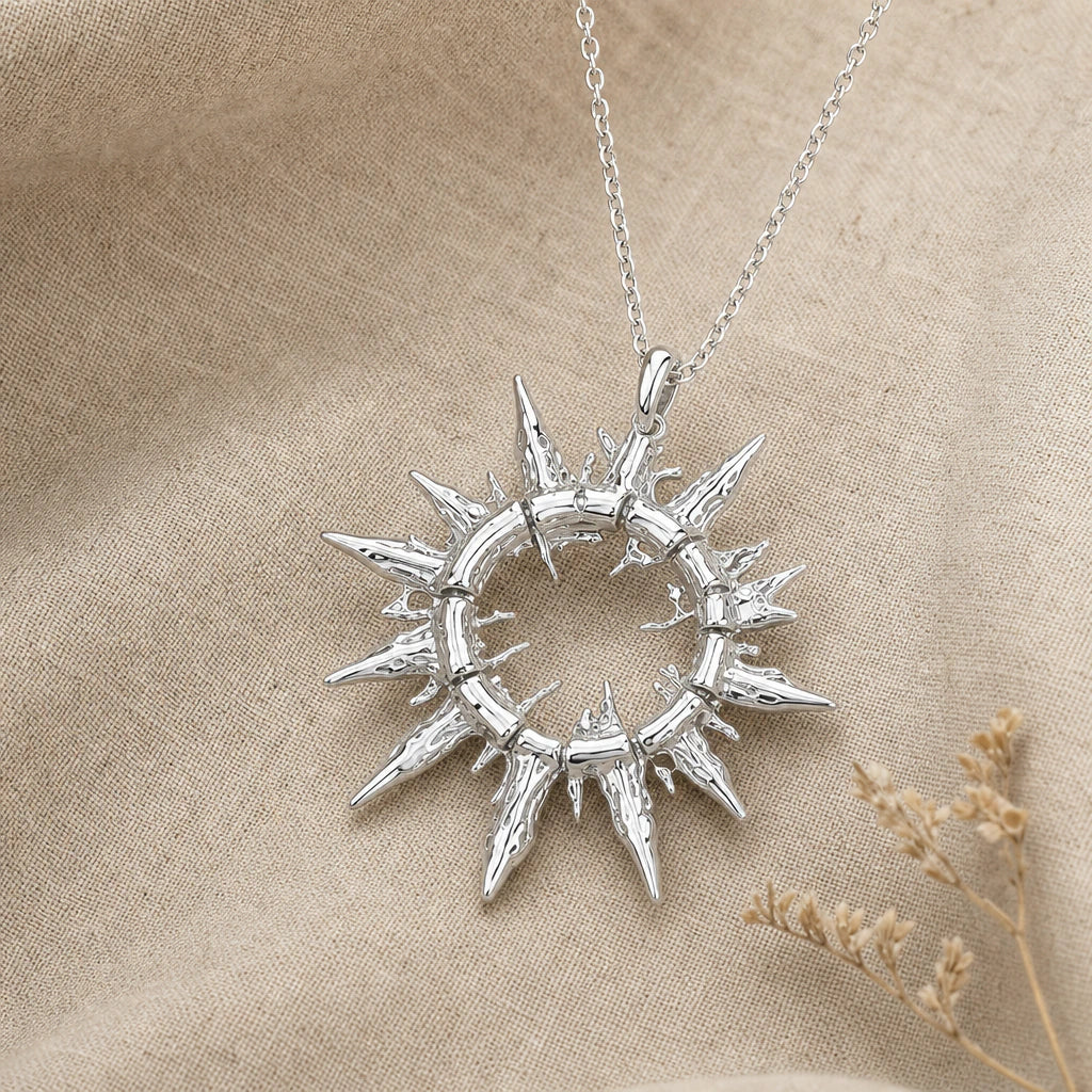 Close-up of silver sun pendant with open ring and jagged rays