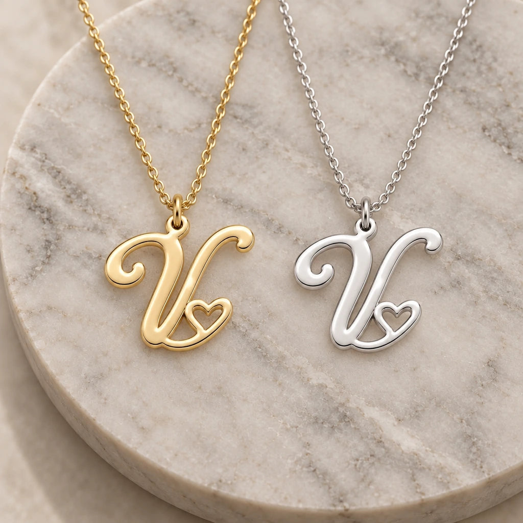 Silver and gold v initial heart pendant necklaces side by side on marble