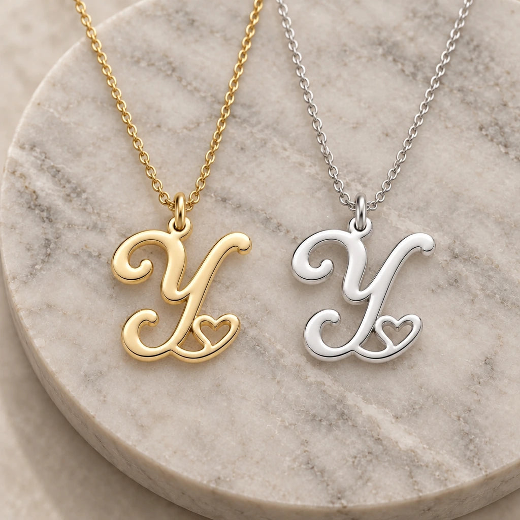 Silver and gold y initial heart pendant necklaces side by side on marble