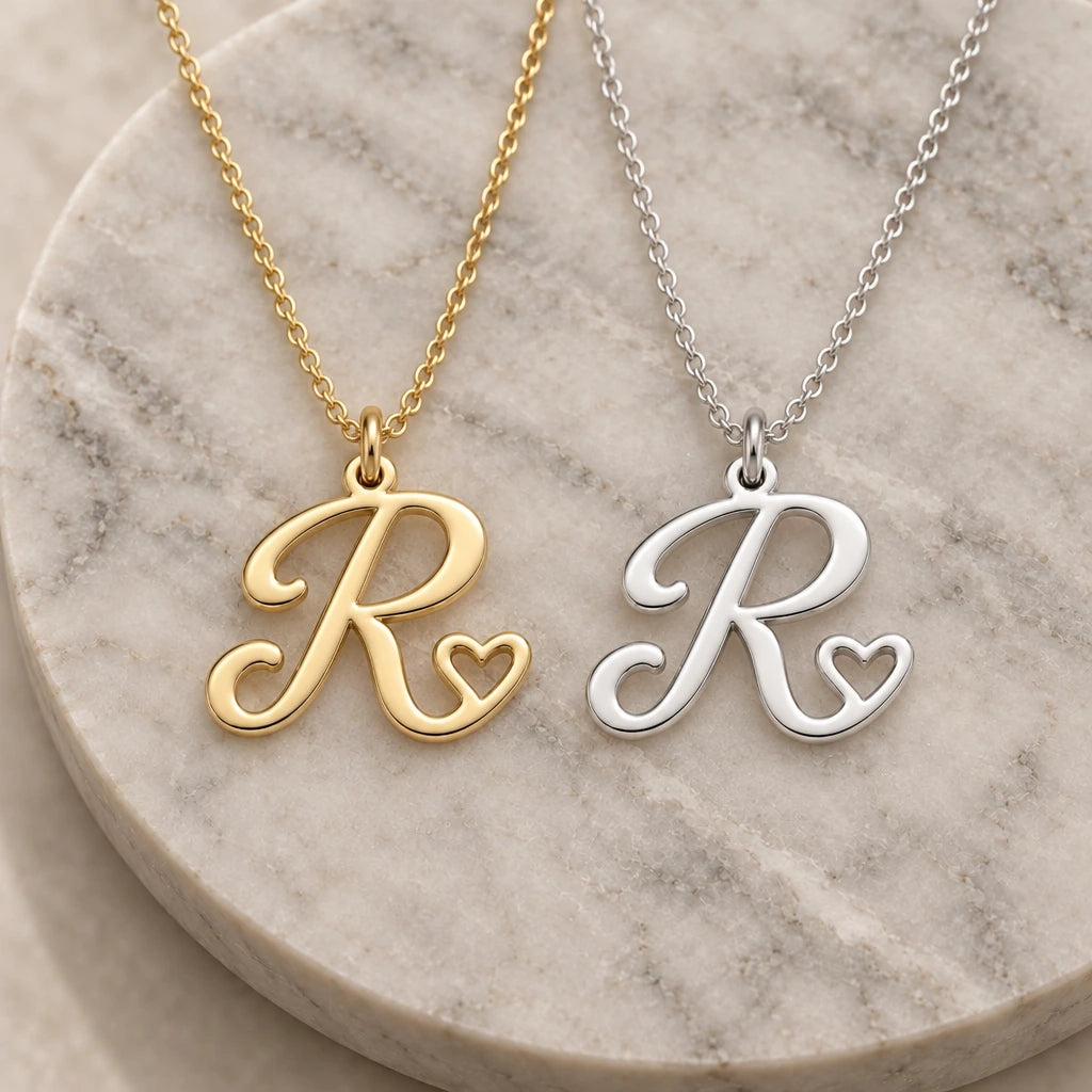 Silver and gold r initial heart pendant necklaces side by side on marble