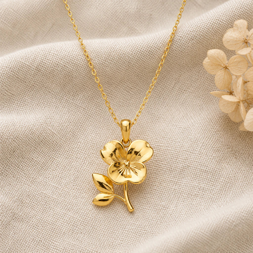 Violet Birth Flower pendant necklace in a warm gold finish on cream fabric