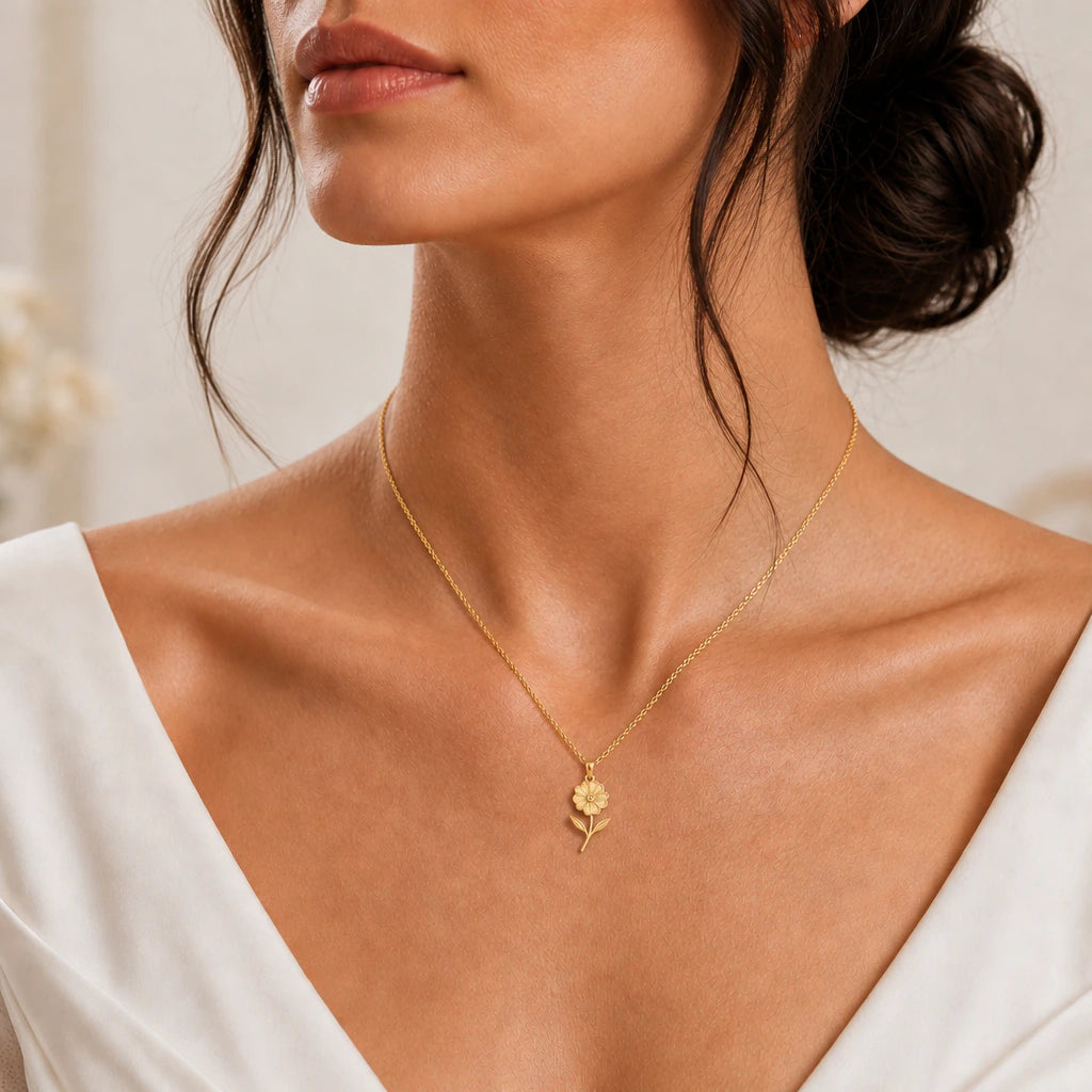 Gold finish primrose pendant necklace worn with an ivory dress close-up