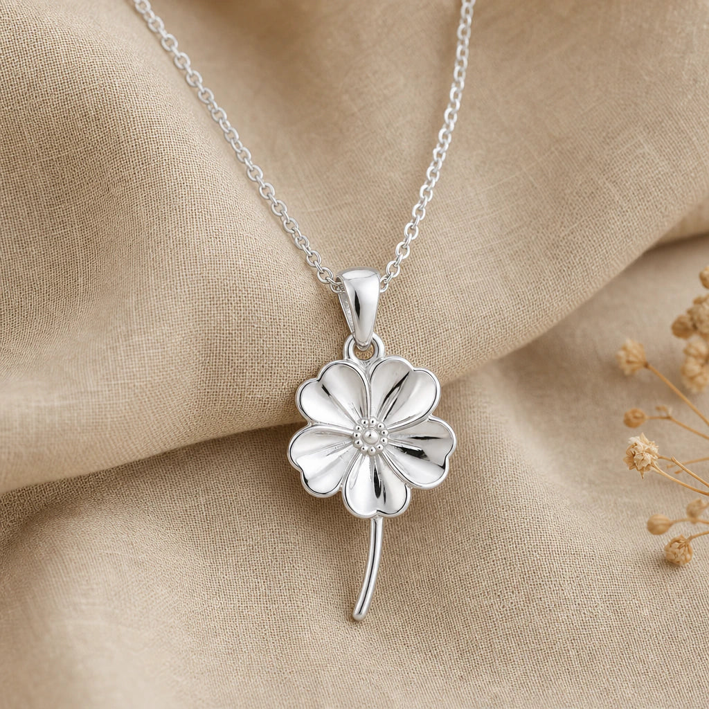 Close-up of silver forget me not pendant with five notched petals, beaded centre and curved stem